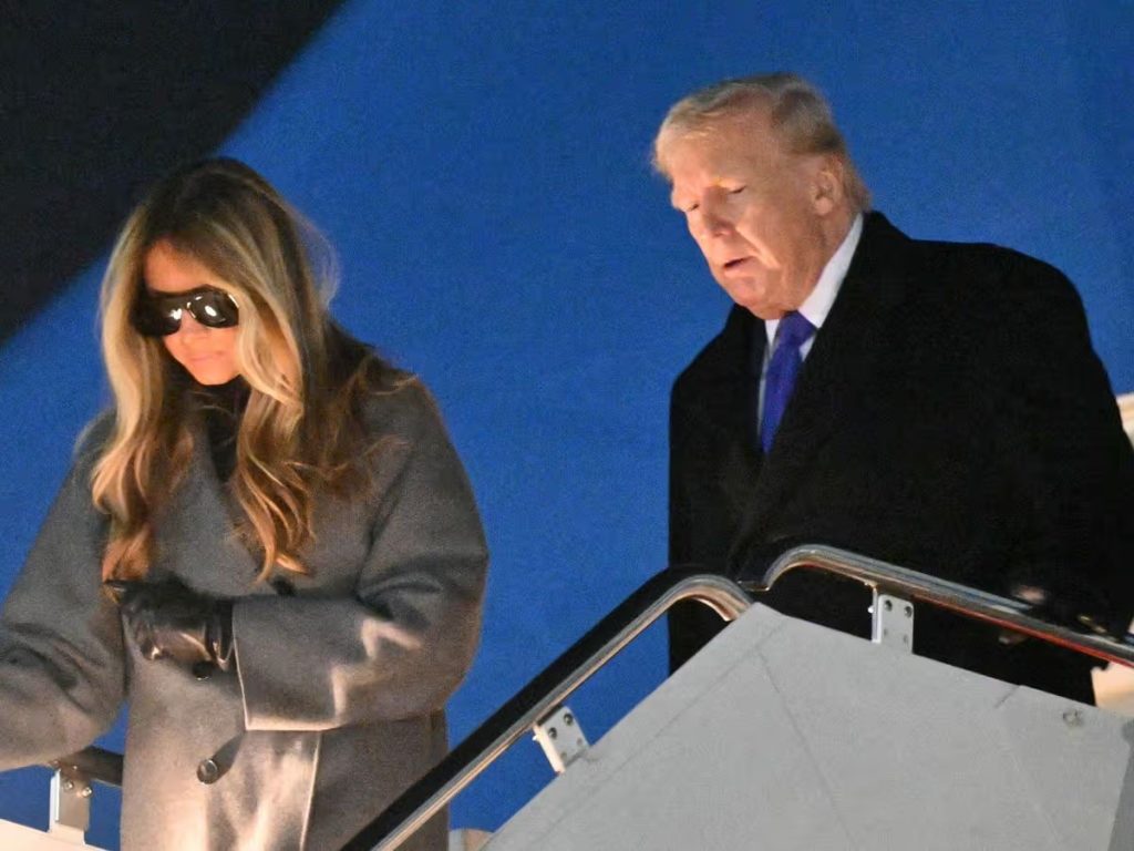 Melania i Donald Trump silaze niz stepenice aviona Air Force One u večernjim satima.